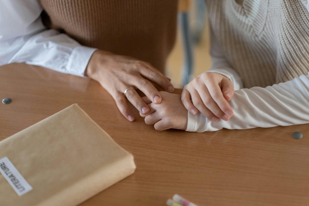 A warm moment captured as comforting hands rest on a table with a book nearby.