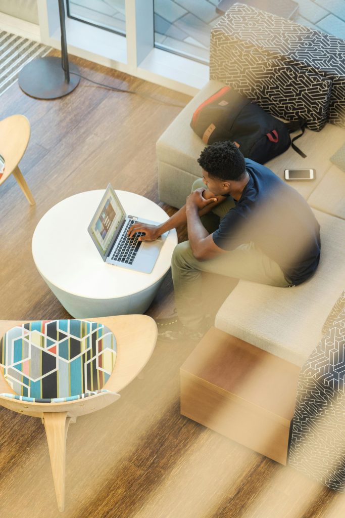 Young man working remotely on laptop in a stylish modern home interior setting.